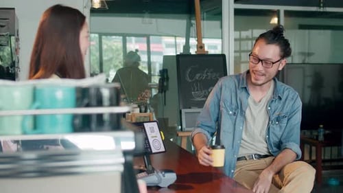 Asia female barista serving take away hot coffee paper cup to consumer standing behind bar.