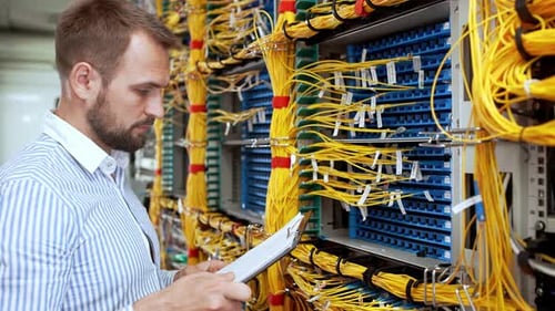 IT Engineer Inspecting Server Cables in Data Center