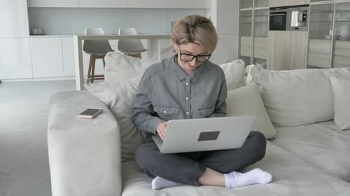 Woman Using Laptop on Couch in Modern Home