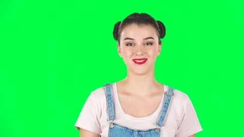 Portrait of Smiling Girl with Two Hair-buns on Green Screen. Slow Motion