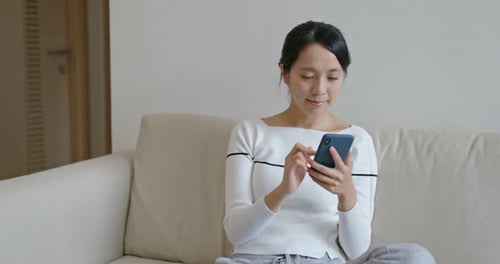 Woman Using Smartphone on Sofa Indoors