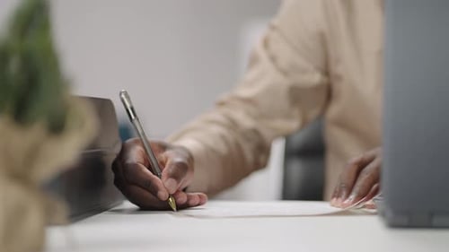 Businessman is Making Notes Writing on Paper Sitting at Table in Working Room Closeup View of Hand