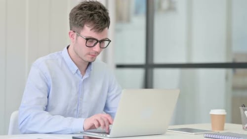 Young Adult Typing at Computer in Office