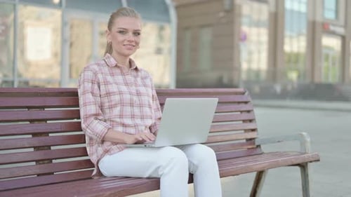 Woman Typing on Laptop on City Bench