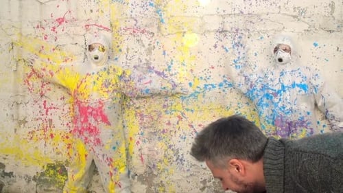 Man Painting Figures in Suits Against Textured Wall