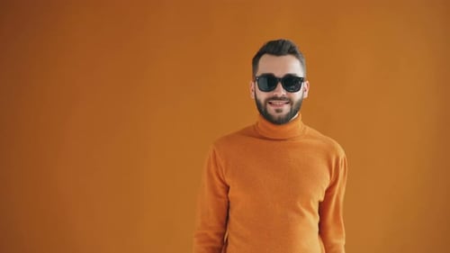 Smiling Man in Orange Removing Sunglasses