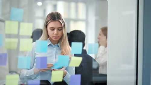 Young Woman Brainstorming With Sticky Notes in Office