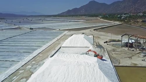Vast Salt Farm with Excavator on Sunny Day