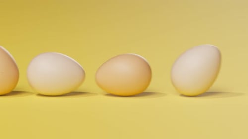 Rolling eggs on a yellow pastel background. Happy Easter. Spring celebration.