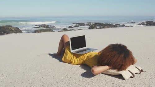 Mulher afro-americana com seu laptop na praia