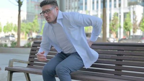 Man Experiences Back Pain on City Bench