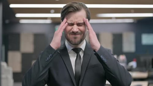 Stressed Businessman Massaging Temples in Office