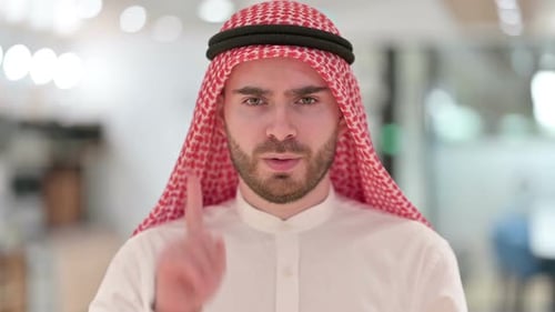 Man in Traditional Headdress Gestures Index Finger Up