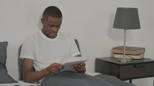 Man Receives Good News Reading Documents in Bed