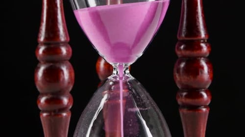 Sand Falls Quickly Through an Hourglass. Black. Close Up