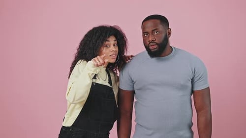 Afroamerikanerin zeigt ihrem Freund etwas, zeigt auf die Kamera, runzelnde Gesichter und