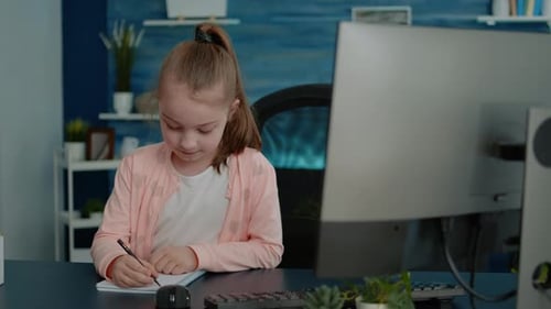 Child Studying and Writing at Desk Indoors