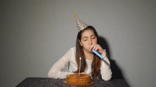 Woman With Birthday Cake Blowing Noisemaker
