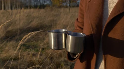Traveler Carries Mugs in Sunny Autumn Field