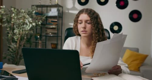 Woman Working From Home With Laptop and Papers