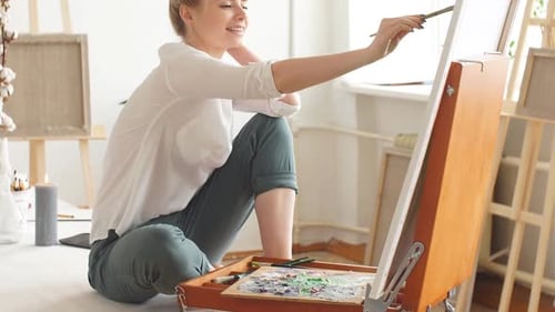 Female Artist Painting on Canvas in Bright Studio