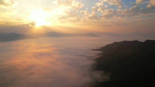 Les rayons du soleil brillent à travers les nuages et pénètrent dans la brume au-dessus des montagnes le matin