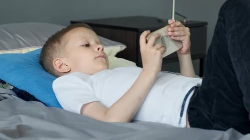Boy Lying on Bed Using Mobile Phone