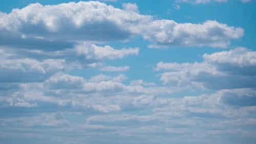 Fluffy White Clouds Drifting in Blue Sky