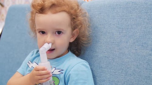 Un niño pequeño inhala con un nebulizador. De cerca