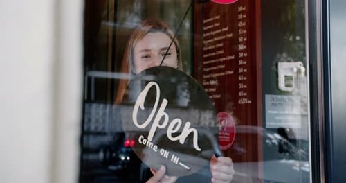 El letrero giratorio del propietario abre la cafetería para los clientes después de la restricción
