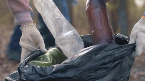 Voluntarios poniendo botellas de plástico en una bolsa de basura