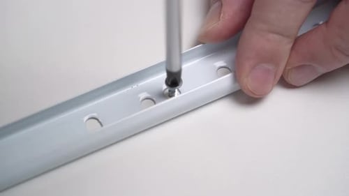 Person Using Screwdriver to Tighten Screw in Metal