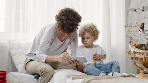 Woman and Child Using Tablet on Bed