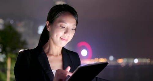 Woman Uses Tablet at Night in the City