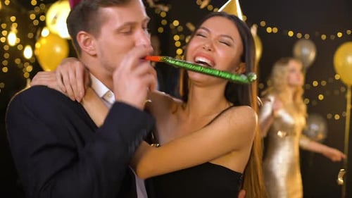 Happy Couple Party Hats Blowing Noisemaker, Enjoying Birthday Celebration, Fun