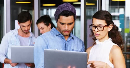 Young Adults Collaborating on Laptops in Modern Office