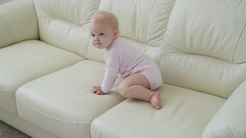 Cute Infant Crawls on Cream Colored Sofa
