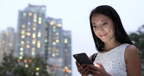 Woman use of cellphone in city at night