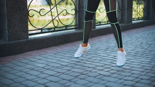 Closeup woman legs exercising and jumping in city park.