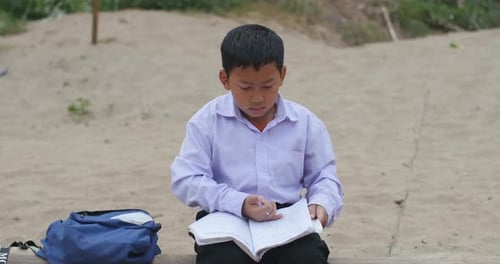 Boy Reading a Book on a Sand