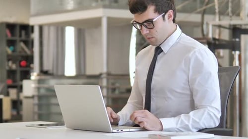 Man Celebrating Success at Laptop in Office