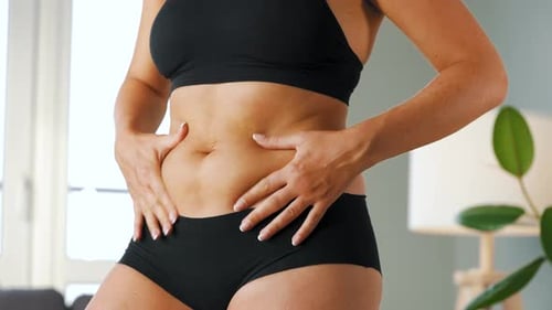 Femme comprimant la peau sur son ventre en vérifiant la cellulite et l'excès de graisse sous-cutanée