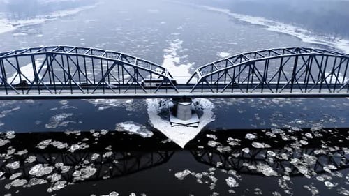 Snowy bridge over river with floe in winter
