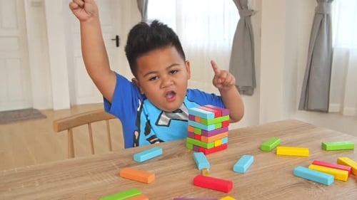 Kleiner Junge tanzt mit farbigem Holzblock Tower Spiel
