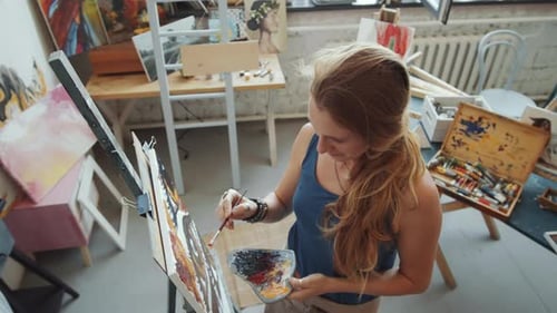 Portrait of Cheerful Female Artist Painting in Studio