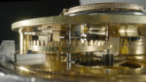 Inside View of a Moving Clockwork of Golden Mechanical Clock on Black Isolated Studio Background