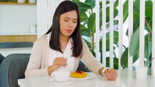 Asian Woman with Cake and Coffee at Cafe