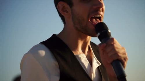 A Young Man Sings on the Street on a Summer Day, He Holds a Microphone