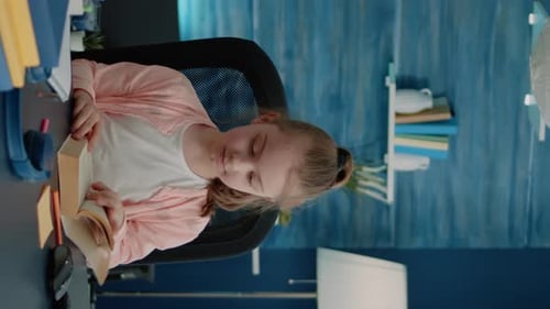 Vertical Video Caucasian Girl Reading Book at Desk for Primary School Work