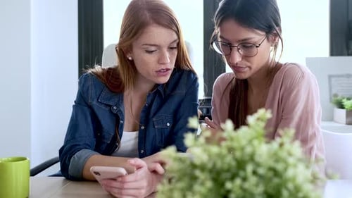 Women Working Together Using Smartphones in an Office